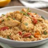A close-up of a white bowl filled with creamy Marry Me Chicken and Rice, featuring tender chicken pieces, sun-dried tomatoes, and herbs garnished with parsley.