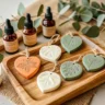 Handmade heart-shaped clay diffuser stones in earthy tones with botanical imprints, displayed on a wooden tray with essential oil bottles and eucalyptus leaves.