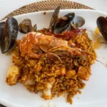 A plate of easy seafood paella with mussels, clams, shrimp, and saffron rice, served on a white dish.