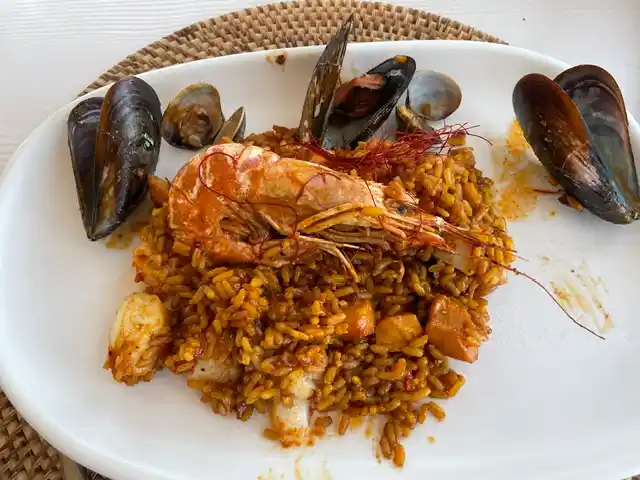 A plate of easy seafood paella with mussels, clams, shrimp, and saffron rice, served on a white dish.