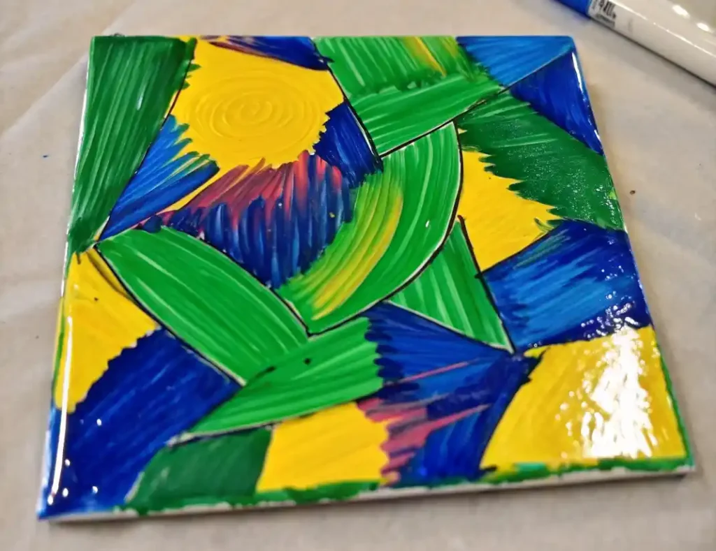 How to Paint With Sharpies and Alcohol: A Beautiful, Budget-Friendly DIY Anyone Can Do 2 Geometric Sharpie marker design on a ceramic tile with green, yellow, blue, and red sections.