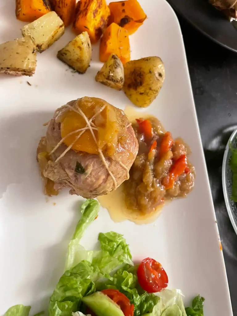 Veal Paupiettes: A Tender French Classic with a Sweet Surprise 3 A veal paupiette topped with a slice of dried apricot and tied with butcher’s string, served with roasted sweet and regular potatoes, braised vegetables, and a fresh salad.